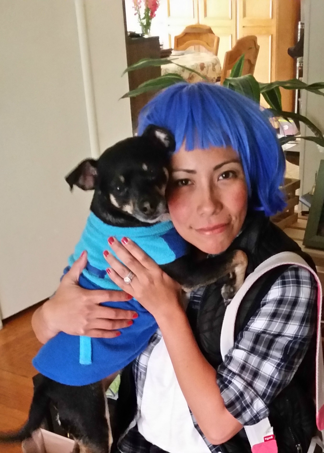 Girl with blue hair and her dog hugging her